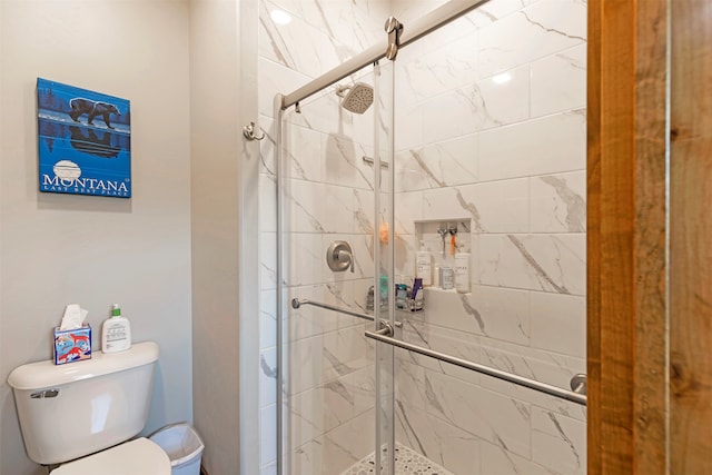 bathroom featuring a shower with shower door and toilet