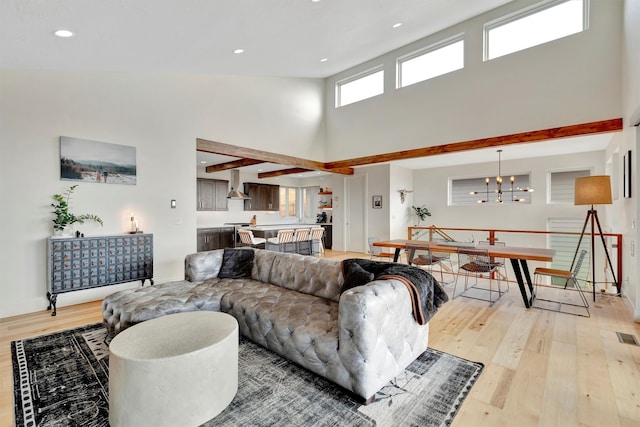 living room with light hardwood / wood-style flooring, a chandelier, and high vaulted ceiling