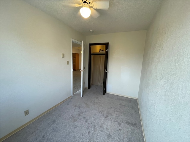 empty room with light colored carpet, a textured ceiling, and ceiling fan