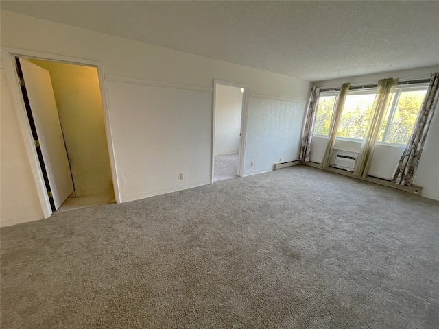 carpeted spare room with a wall mounted AC and a textured ceiling