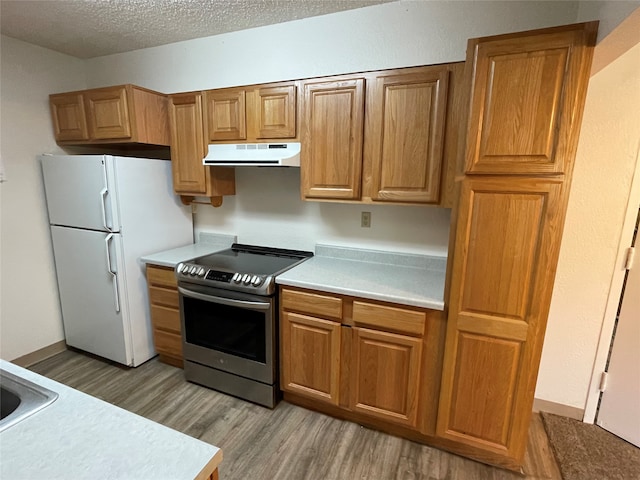 kitchen featuring white refrigerator, stainless steel electric range oven, light hardwood / wood-style floors, and a textured ceiling