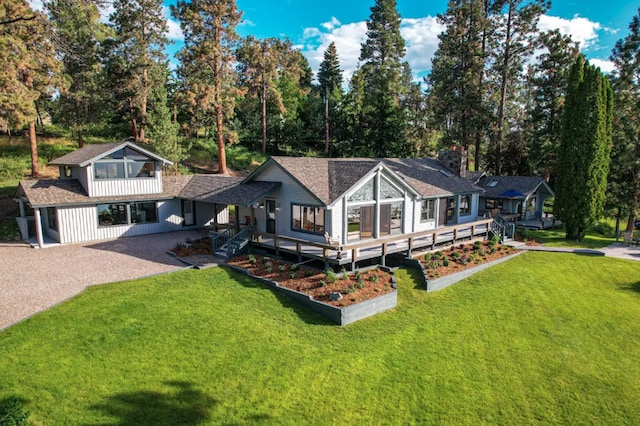 22700 Northaire Ln, Rollins, MT 59931 - back of property with gravel driveway, a lawn, a garden, and a shingled roof