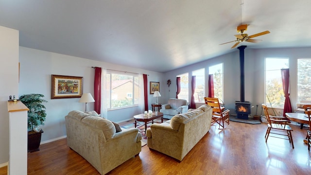 52772 Herak Rd, Charlo, MT 59824 - living area with baseboards, lofted ceiling, a ceiling fan, wood finished floors, and a wood stove