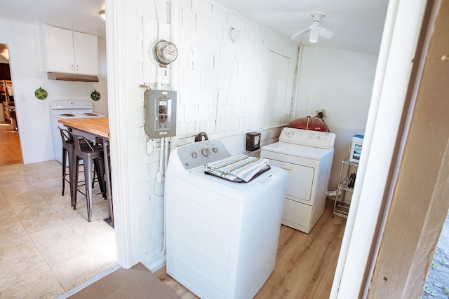 laundry room featuring light wood-type flooring, ceiling fan, washer and clothes dryer, and electric panel