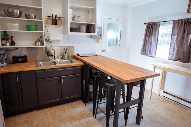 kitchen with dark brown cabinets, butcher block countertops, sink, and a baseboard heating unit