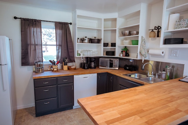 kitchen with light tile patterned flooring, wooden counters, white appliances, and sink