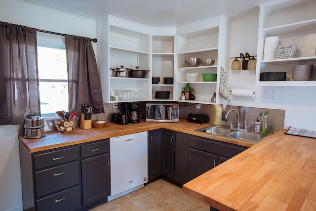 kitchen with light tile patterned flooring, wooden counters, crown molding, sink, and white dishwasher