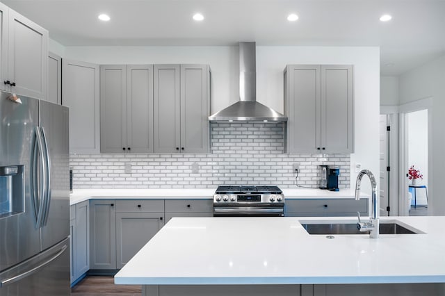 kitchen featuring wall chimney exhaust hood, sink, appliances with stainless steel finishes, and gray cabinetry