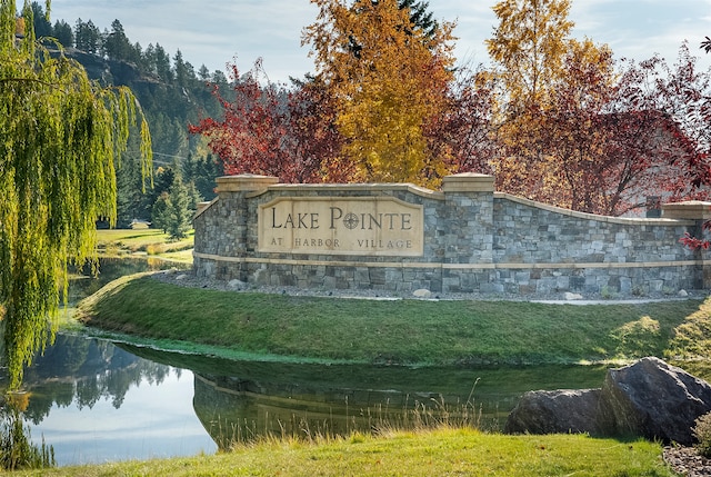 community sign with a lawn and a water view