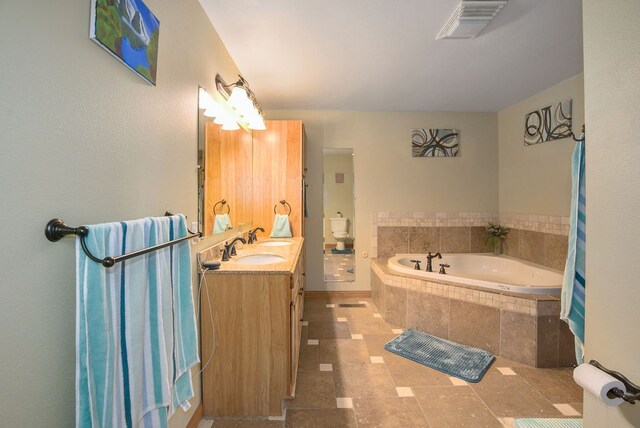 bathroom featuring tiled tub and vanity