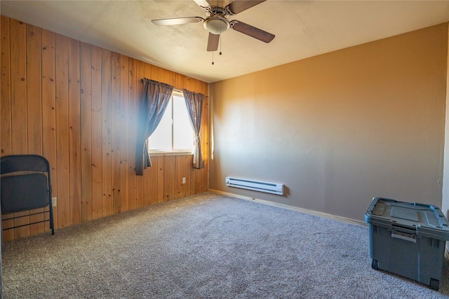 unfurnished room featuring baseboard heating, wood walls, carpet, and ceiling fan