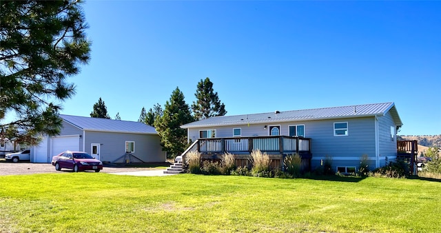 rear view of property featuring a deck, a yard, and a garage