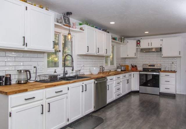 kitchen with white cabinets, appliances with stainless steel finishes, butcher block counters, dark wood-type flooring, and decorative light fixtures