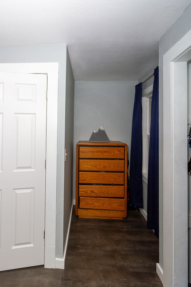 hall featuring a textured ceiling and dark hardwood / wood-style floors