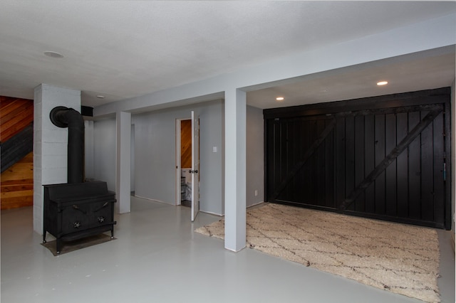 basement with a wood stove, a textured ceiling, and wooden walls