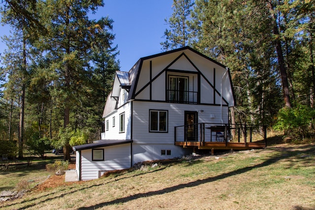 rear view of house featuring a deck, a yard, and a balcony