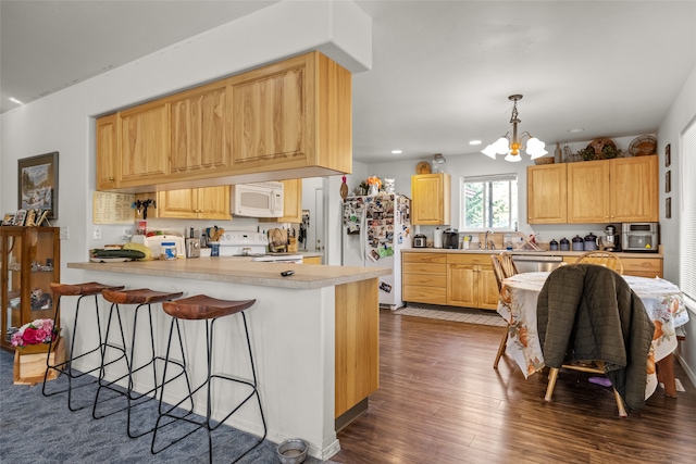 kitchen with hanging light fixtures, kitchen peninsula, light brown cabinetry, white appliances, and dark hardwood / wood-style flooring