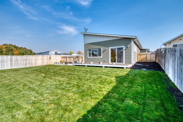 rear view of house featuring a yard and a deck