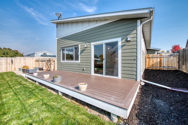 rear view of property featuring a deck and a lawn