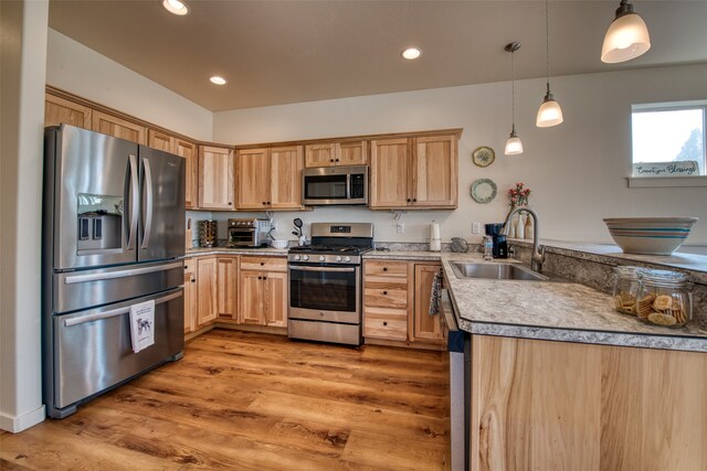 kitchen with hanging light fixtures, stainless steel appliances, sink, light wood-type flooring, and light brown cabinetry