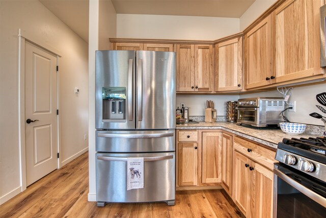 kitchen featuring light brown cabinets, stainless steel appliances, and light wood-type flooring