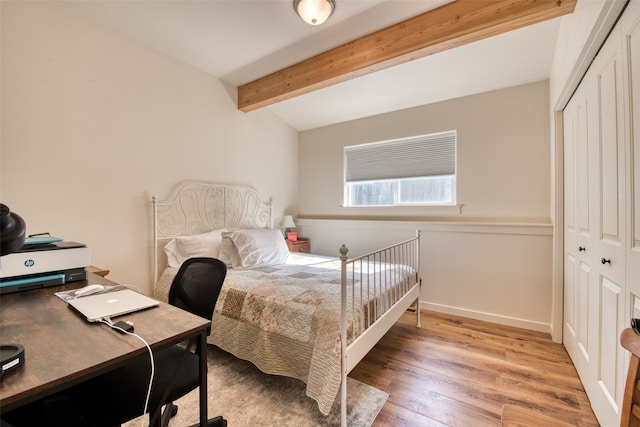 bedroom with a closet, beamed ceiling, and wood-type flooring