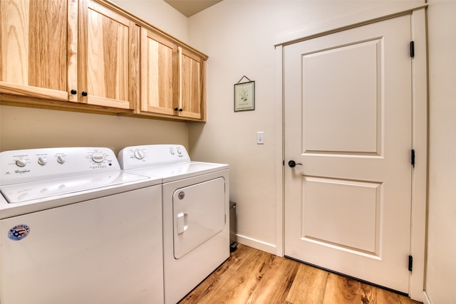 laundry room with washing machine and dryer, light hardwood / wood-style flooring, and cabinets