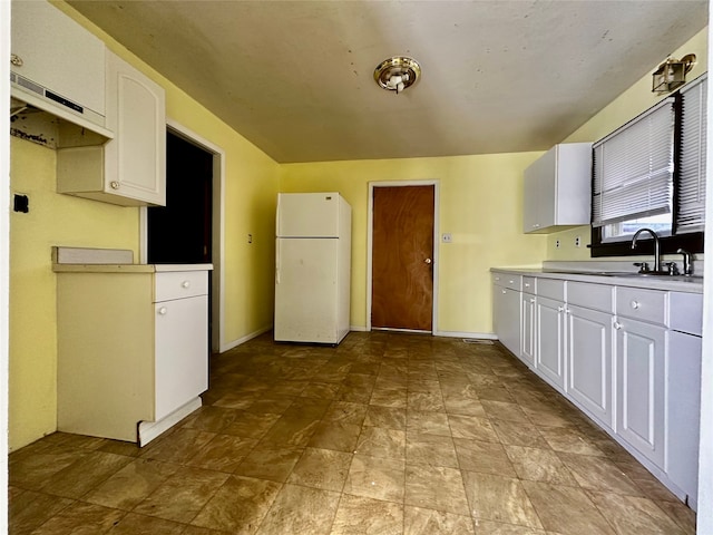 kitchen featuring white cabinetry, white fridge, and sink