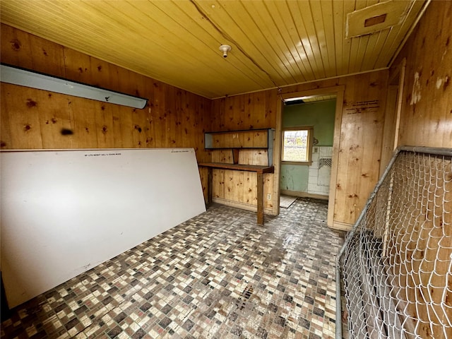 empty room featuring wood ceiling and wood walls