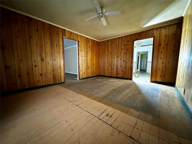 unfurnished room featuring wood-type flooring, ornamental molding, wooden walls, and ceiling fan