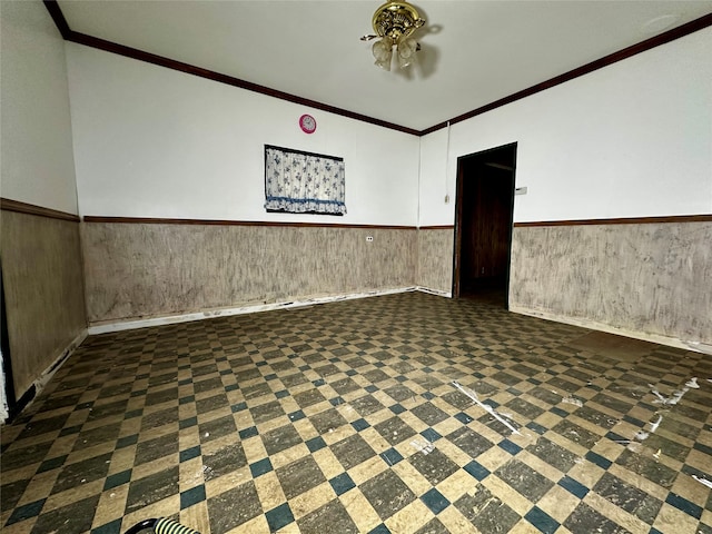 spare room with crown molding and wooden walls