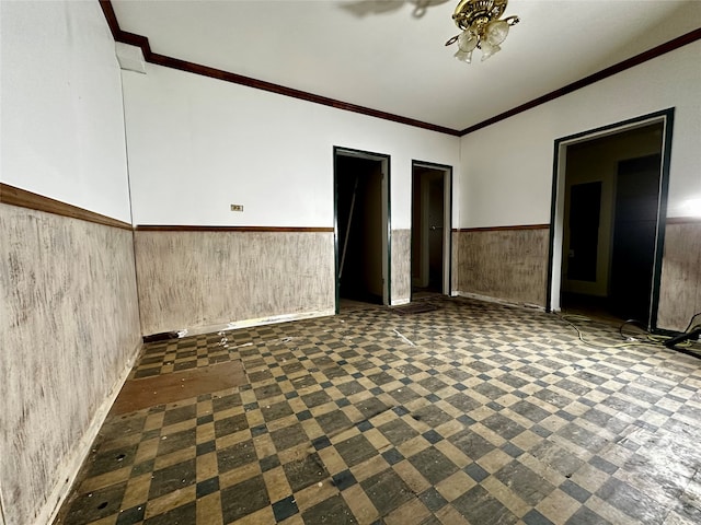 empty room featuring ornamental molding and wood walls