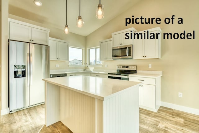 kitchen featuring a kitchen island, white cabinets, vaulted ceiling, pendant lighting, and appliances with stainless steel finishes