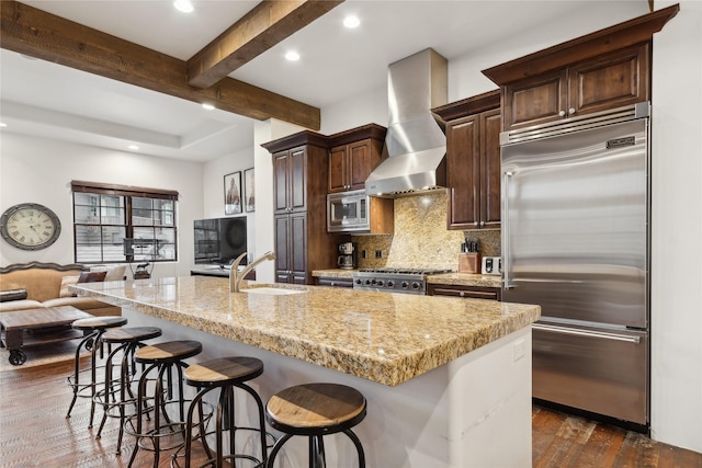 89 Slopeside Dr Unit 4, Whitefish, MT 59937 - kitchen featuring built in appliances, wall chimney range hood, dark wood-style floors, a breakfast bar, and decorative backsplash