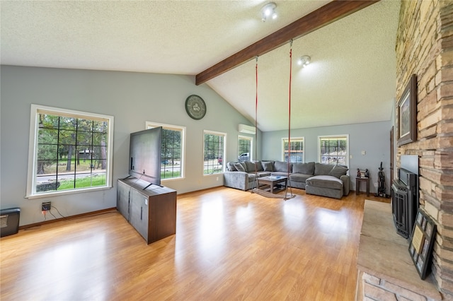 living room featuring a wall mounted air conditioner, a fireplace, light hardwood / wood-style floors, beam ceiling, and high vaulted ceiling