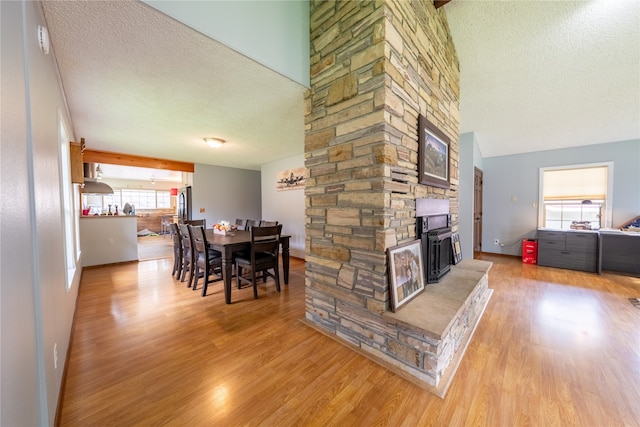 dining room with light hardwood / wood-style floors, a textured ceiling, and a healthy amount of sunlight