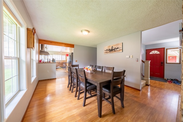 dining room with a textured ceiling, light wood-type flooring, and plenty of natural light