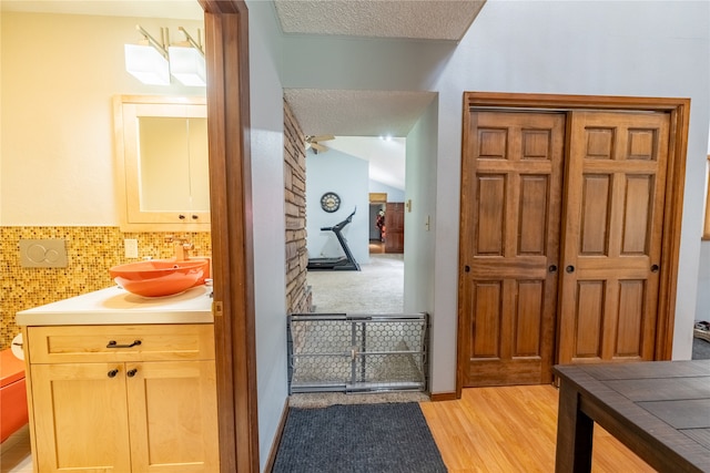 corridor featuring light hardwood / wood-style floors, a textured ceiling, and sink