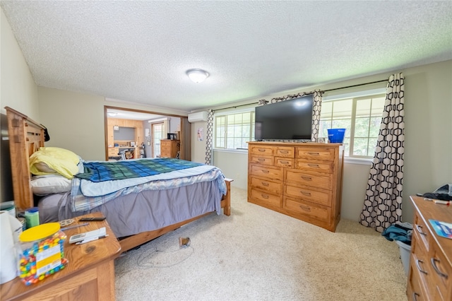 bedroom with light carpet, multiple windows, a textured ceiling, and a wall mounted AC