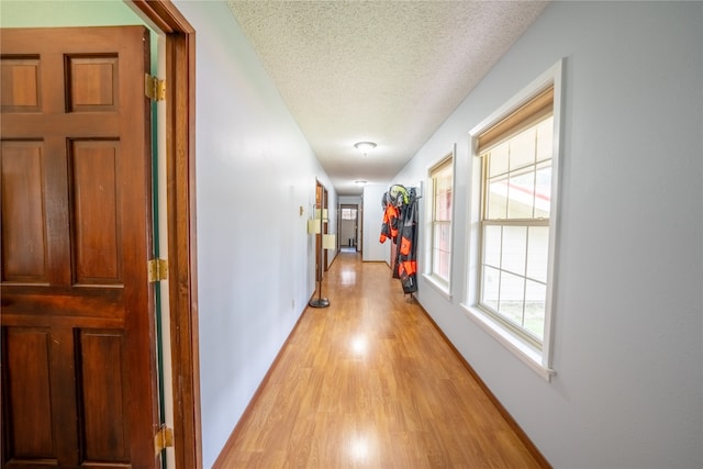 corridor with a textured ceiling and light wood-type flooring