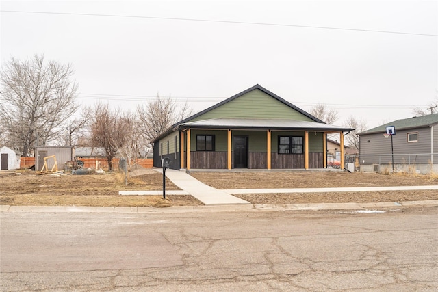 view of front of home featuring covered porch and a shed