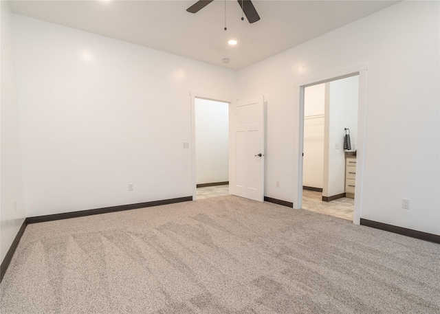 unfurnished bedroom with ceiling fan, light colored carpet, a walk in closet, and a closet