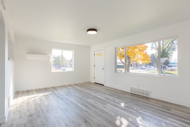 interior space with light hardwood / wood-style floors and a wall unit AC