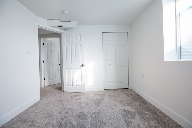 unfurnished bedroom with light carpet and a closet