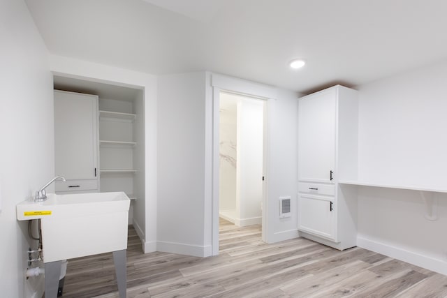 laundry area featuring light hardwood / wood-style flooring and heating unit