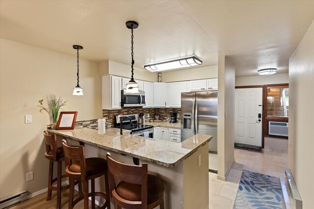 kitchen featuring kitchen peninsula, white cabinetry, appliances with stainless steel finishes, light stone counters, and tasteful backsplash