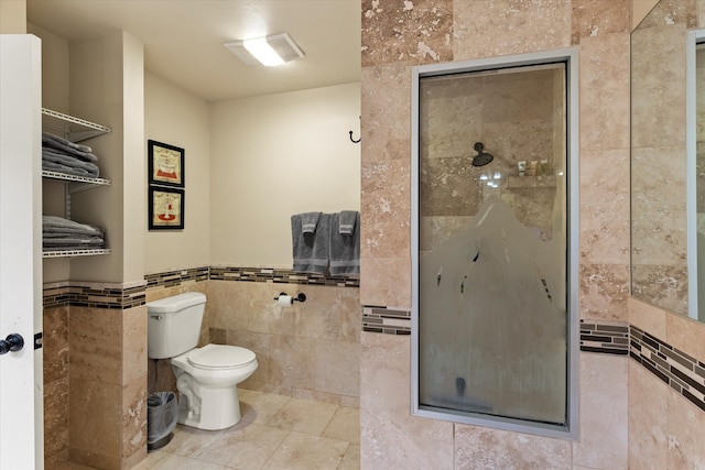 bathroom featuring toilet, tile walls, and a shower with shower door