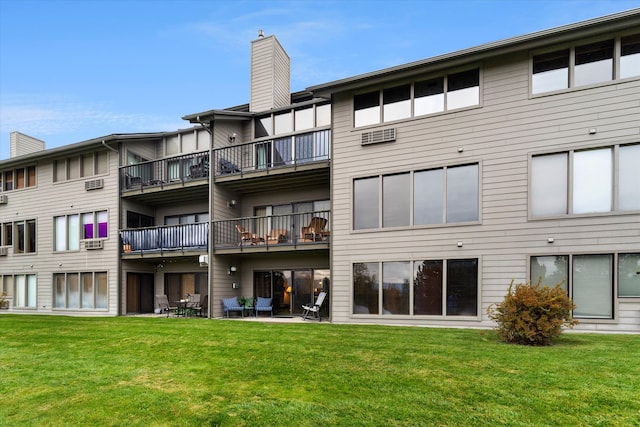 back of house featuring a balcony, a patio, and a lawn