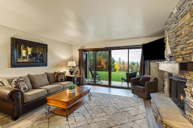 living room featuring light hardwood / wood-style floors, a textured ceiling, and a fireplace