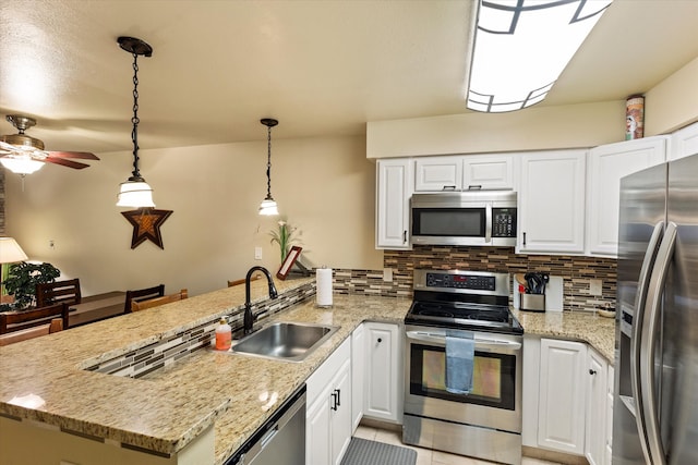 kitchen featuring hanging light fixtures, kitchen peninsula, sink, white cabinets, and appliances with stainless steel finishes